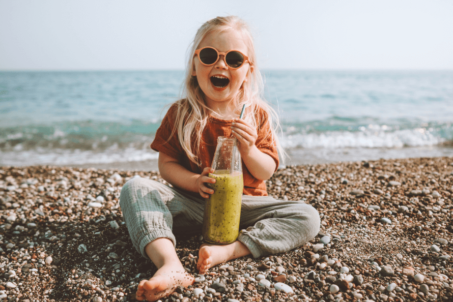 child on the beach with a snack 